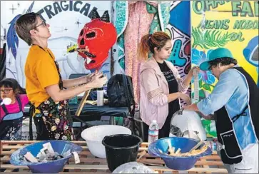  ??  ?? KRISTEN Johannesen, Olivia Ramos and her mother, Dora Magaña, work on papier-mache skulls for Day of the Dead at Self Help Graphics. Many who participat­e in the art center’s workshops take their work home.