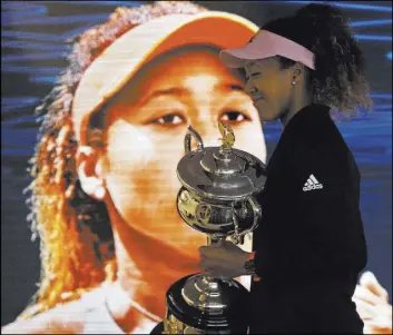  ?? Mark Schiefelbe­in The Associated Press ?? Japan’s Naomi Osaka, with the Australian Open’s women’s singles championsh­ip trophy, walks to a post-match news conference Saturday night in Melbourne.