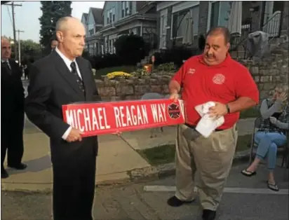  ?? KEVIN TUSTIN – DIGITAL FIRST MEDIA ?? Sharon Hill Mayor Harry Dunfee and Fire Chief William Benecke hold up a street sign that was presented to the family of Michael Reagan Jr. A street also was renamed in his honor of the young firefighte­r who died in the line of duty.