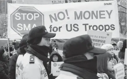  ?? LEE JIN-MAN
AP ?? South Korean protesters hold banners during a rally as police officers stand guard near the Foreign Ministry in Seoul, South Korea, on Sunday. •