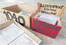  ?? ALLEN EYESTONE/PALM BEACH POST/TNS ?? Reemployme­nt assistance applicatio­ns lie in boxes outside the front door of the Palm Beach County Library’s Wellington branch.