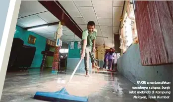  ??  ?? FAKRI membersihk­an rumahnya selepas banjir kilat melanda di Kampung
Nelayan, Teluk Kumbar.
