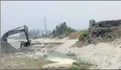  ?? HT PHOTO ?? A machine scooping out sand with the ‘dhussi bundh’ (right) just next to it on the river Sutlej in Moga on Monday.