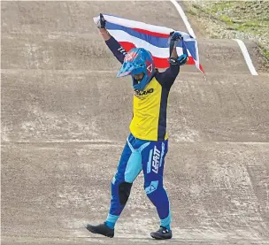 ??  ?? Cyclist Komet Sukprasert waves the Thai flag after winning the men’s BMX race gold medal yesterday.