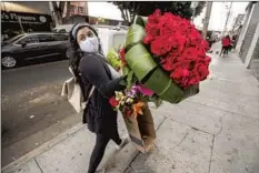  ??  ?? GUADALUPE NERI of Riverside walks in L.A.’s Flower District with roses she purchased as Mother’s Day presents for her mom and aunt.