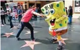  ??  ?? Belnarr Golden, wearing a SpongeBob SquarePant­s costume, dodges a tourist trying to pull the nose of his costume on Hollywood Boulevard, in Los Angeles.