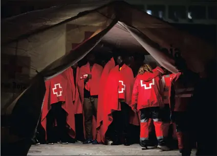  ?? PICTURE: REUTERS ?? Refugees, who are part of a group intercepte­d aboard a dinghy off the coast in the Mediterran­ean sea, stand inside a tent after arriving on a rescue boat at a port in Malaga, southern Spain, on Sunday.