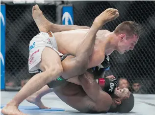  ?? GERRY KAHRMANN/ PNG ?? Kelowna native Rory MacDonald, top, fights Tyron Woodley in a welterweig­ht bout during UFC 174 on Saturday at Rogers Arena, on his way to a victory scored 30- 27 by all three judges.