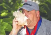  ?? MARY MARTIN/FLORIDA KEYS NEWS BUREAU VIA AP ?? Brian Cardis demonstrat­es his prowess as he blows a conch shell following his Saturday men’s division victory at the Conch Shell Blowing Contest in Key West, Fla.