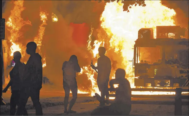  ?? Sean Krajacic The Associated Press ?? Garbage and dump trucks were set ablaze last Sunday by rioters in the aftermath of the Jacob Blake shooting in Kenosha, Wis.