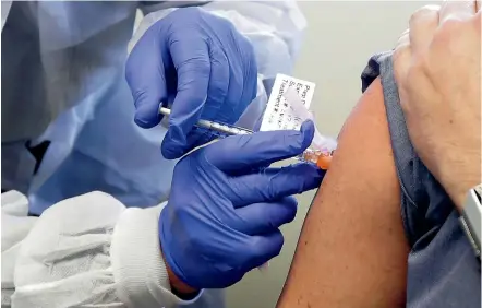  ?? AP ?? A volunteer receives a shot in the first-stage safety study clinical trial of a potential vaccine for Covid-19, at the Kaiser Permanente Washington Health Research Institute in Seattle. The vaccine by Cambridge, Massachuse­tts-based Moderna Inc, generated antibodies similar to those seen in people who have recovered from Covid-19 in a study of volunteers who were given either a low or medium dose.