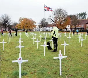  ??  ?? People observe sea of white crosses in Wooburn Green. Ref:133165-5