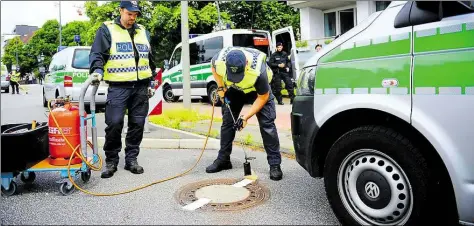  ?? DPA-BILD: REINHARDT ?? Polizisten versiegeln am Dienstag in Hamburg im Vorfeld des G20-Gipfels einen Kanaldecke­l.