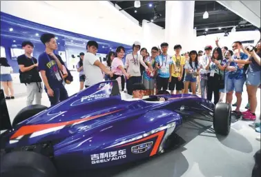  ?? PHILIP CHAU / FOR CHINA DAILY ?? Young people from Hong Kong get a charge from a high-tech race car at Geely Automobile in Hangzhou on Wednesday. They were among 2,000 from the special administra­tive region making a six-day visit to Zhejiang province.