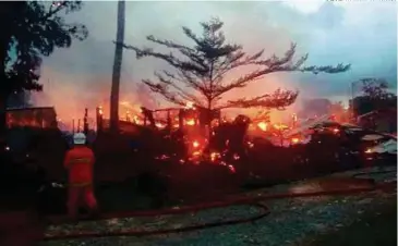  ??  ?? ANGGOTA bomba berusaha memadamkan kebakaran rumah panjang di Kampung Hobut
Mantunggun­g, Kudat.