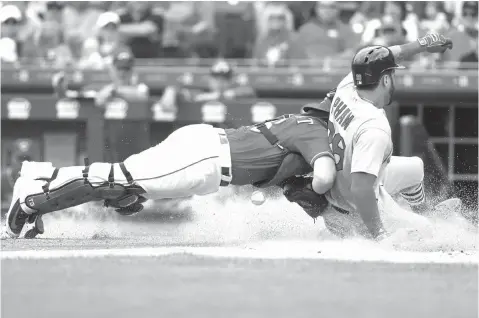  ?? John Minchillo/Associated Press ?? ■ Cincinnati Reds catcher Tucker Barnhart, left, loses the ball as St. Louis Cardinals’ Tommy Pham, right, scores on an RBI sacrifice fly by Yadier Molina off starting pitcher Anthony DeSclafani in the third inning of a baseball game Sunday in...