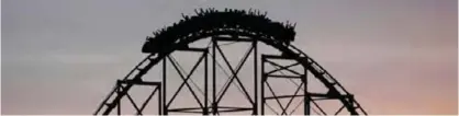  ??  ?? People ride a rollercoas­ter at dusk at Worlds of Fun amusement park on Monday in Kansas City, Montana. — AP