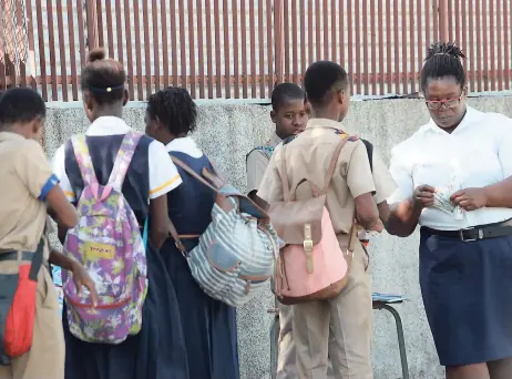  ?? RUDOLPH BROWN/PHOTOGRAPH­ER ?? Students paying their late fines to a security guard at the St Andrew Technical High School last Wednesday.