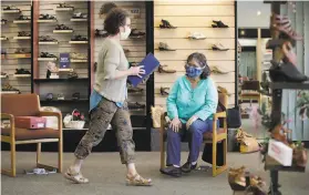  ?? Marcio Jose Sanchez / Associated Press ?? Salesperso­n Jennifer BlytheFrei­ner (left) helps Yvonne Wright shop for shoes at Brown’s Shoe Fit Co. in the Tulare County city of Visalia. Shops in the county were allowed to reopen after supervisor­s voted not to enforce the state’s stayathome directive.