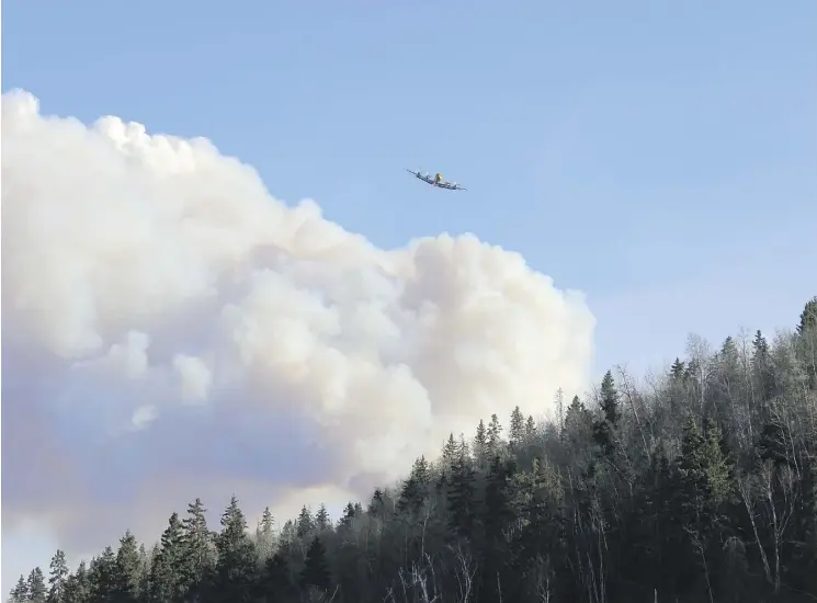  ?? STEPHANIE JELLET/FILE ?? A water bomber heads from one fire to the next over Highway 63 in Fort McMurray on May 1, 2016.