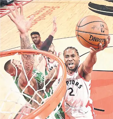  ?? RON TURENNE GETTY IMAGES ?? Raptor Kawhi Leonard lays in two of his 21 points in Tuesday night’s 118-95 cruise over Boston Celtics. They split the season series 2-2, and the Raptors are done with the other East contenders for the regular season.