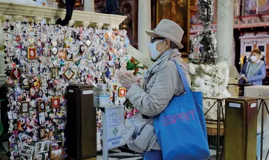  ??  ?? Preghiere e statua
A fianco, una fedele in Basilica; nella foto a destra, il busto dorato del Santo, con la reliquia «massa corporis», ieri per il volo di prova