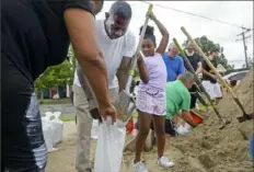  ?? Max Becherer/ The Advocate via AP ?? Nyla Trepagnier, center, fills a sandbag held by her grandparen­ts at a sandbag station Friday in New Orleans, La. The storm system in the Gulf of Mexico is expected to make landfall, possibly as a hurricane, near Morgan City on Saturday morning.