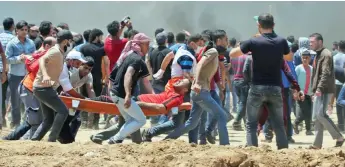  ??  ?? Un Palestinie­n blessé par des tirs israéliens évacué par d’autres manifestan­ts, hier, dans la bande de Gaza, à la frontière avec Israël