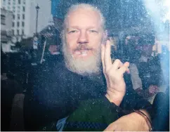  ?? JACK TAYLOR / GETTY IMAGES ?? WikiLeaks founder Julian Assange gestures to reporters as he is driven into court in London on Thursday.