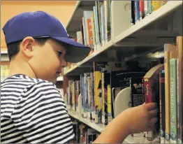  ??  ?? photo
Signal file Jake Lara, 7, looks through books at the Old Town Newhall Library in September. Los Angeles County board supervisor­s recently approved fine-free library cards for youth.