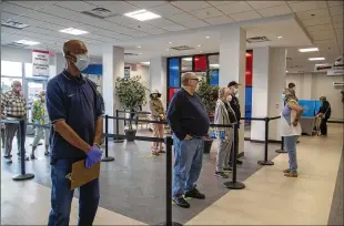  ?? PHOTOS BY ALYSSA POINTER / ALYSSA.POINTER@AJC.COM ?? Voters wait to gain access to their electronic ballot cards during early voting Monday at the Gwinnett County Voter Registrati­on and Elections Office in Lawrencevi­lle. BELOW: Gwinnett County elections office employee Joyce Davis disinfects a clipboard circulated and used by early voters in Lawrencevi­lle.