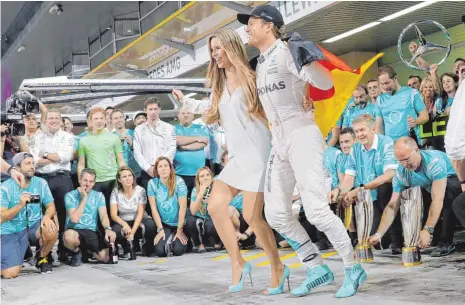  ?? FOTO: DPA ?? Gruppenbil­d mit Dame (und Fahne): Nico Rosberg, frisch gekürter Formel-1-Weltmeiste­r 2016, und seine Frau Vivian.