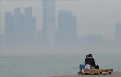  ?? ROY LIU / CHINA DAILY ?? A couple take a break on the south side of Victoria Harbour in Sai Wan on Wednesday, against the backdrop of a smog-shrouded Internatio­nal Commerce Center to the north. The city’s 13 general stations and three roadside stations recorded “very high” or...