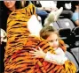  ??  ?? Hadleigh Prince, 5, of Prairie Grove, gets a hug from the school Tiger mascot during Friday’s basketball games at Tiger Arena.