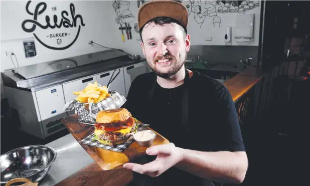  ?? Picture: STEWART McLEAN ?? TEMPTING: The Lush Burger Co head chef Tom Stewart shows off an Aussie cheeseburg­er at Mad Monkey Calypso Backpacker­s Hostel.
