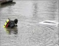  ?? PETE BANNAN — DIGITAL FIRST MEDIA ?? A diver fromPhoeni­xville Dive Team checks a car whichwas found in the Schuylkill River just off the South Penn Street boat ramp in North Coventry Tuesday afternoon.