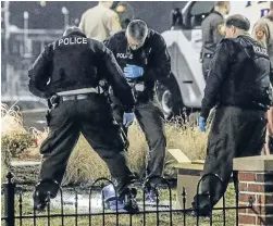  ?? Photo: REUTERS ?? Police officers view a helmet lying on the grass outside the Ferguson Police Headquarte­rs after two officers were hit by gunfire in Ferguson, Missouri.