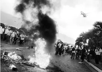  ??  ?? MANIFESTAN­TES venezolano­s prenden hogueras en las afueras de Caracas.