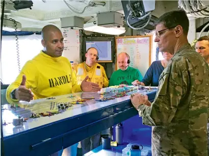  ??  ?? Gen. Joseph Votel, the top US commander for the Middle East, gets a briefing on the USS Nimitz, from Lt. Cmdr. Vern Jensen, the aircraft handling officer for the ship. The Nimitz is in the Gulf, and fighter jets are flying off the aircraft to conduct...