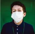  ??  ?? David Melendez, 12, who lives near the warehouse that burned down Thursday, wears a mask Friday as he prepares to go to school in Spring Branch.