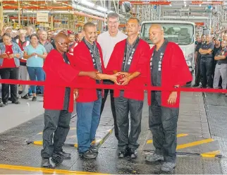  ??  ?? Isuzu trucks and D-Max ranges are now built alongside each other at the company’s new manufactur­ing plant in Port Elizabeth, left. Above: IMSA CEO Michael Sacke poses with some of the company’s longest-serving members as they cut the ribbon.