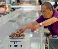  ?? AFP ?? A man getting food from a robot at the ROBOT.HE restaurant in Shanghai. —