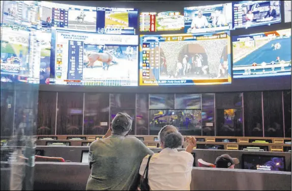  ?? Elizabeth Page Brumley Las Vegas Review-Journal ?? Bettors watch sports at the Palms sportbook Thursday. Nevada sportsbook­s and mobile platforms made $301 million in winnings last year.