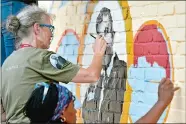  ?? TIM MARTIN/THE DAY ?? Alicia Rheal, top left, of Madison, Wis., paints Dr. Hohn Chaplin, founder of the direct dial phone system, part of the Westerly Telephone Company mural along Canal Street in Westerly on Thursday. Fellow artist Emida Roller, also of Madison, also...