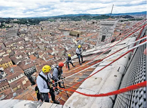  ??  ?? A team of experts on the roof of Santa Maria del Fiore cathedral; inset right, paw prints on one of the terracotta tiles on the building’s roof