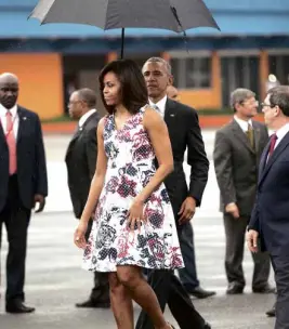  ?? AP ?? US PRESIDENT Barack Obama holds an umbrella for first lady Michelle Obama as they walk across the tarmac of Jose Marti Internatio­nal Airport in Havana, Cuba.