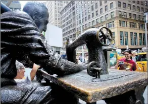  ?? AP/BEBETO MATTHEWS ?? Tourists take photos at The Garment Worker, a bronze sculpture at the edge of New York’s garment district.