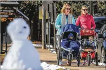  ?? JOHN SPINK / JSPINK@AJC.COM ?? Things were beginning to thaw out Monday at Chastain Park in Atlanta where Katy Cahill and Katie Baldwin strolled their sons by a snowman left on a park bench.