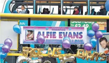  ??  ?? ► Un bus pasa junto a globos y pósters en apoyo de Alfie Evans, en Liverpool.