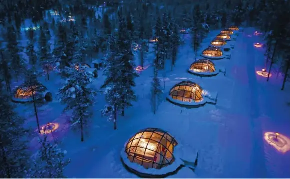  ?? KAKSLAUTTA­NEN.FI ?? The light from Kakslautta­nen Arctic Resort’s glass igloos pierces a wintry night in northern Finland. Outside it’s sub-zero, but inside the igloo it’s toasty warm.